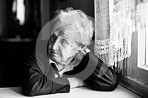 Elderly woman sitting in the kitchen near the window