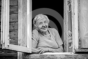 An elderly woman sitting and looking out the window. Black and white photo.