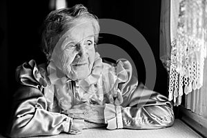 An elderly woman sitting near the window.