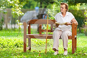 Elderly woman sitting and relaxing on a bench in park