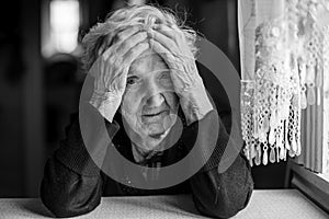 Elderly woman sitting at a table in a depressed state.