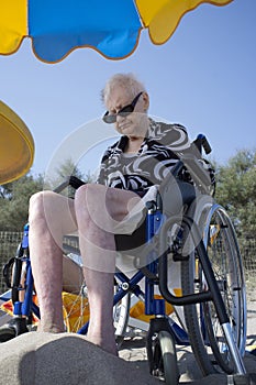 Elderly woman sitting in a wheelchair on the beach