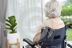 An elderly woman sitting on wheelchair looking out the window for waiting someone. Sadly, melancholy and depressed