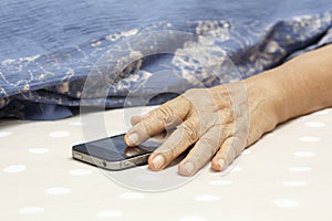 Elderly woman sleeping and holding a mobile phone.