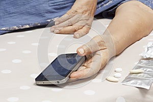 Elderly woman sleeping and holding a mobile phone.