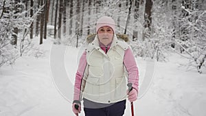 The elderly woman spends leisure-time in the wood. Winter forest. The woman supports the level of physical activity. The