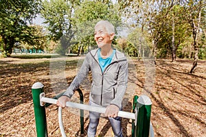 Elderly Woman In Sports Clothes Exercising At Outdoor Fitness Park