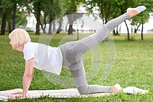 elderly woman in sportswear practicing yoga on mat