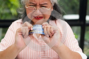 An elderly woman stressed about her finances is debiting her credit card.