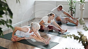 Elderly woman stretches and prepares to perform Jana Shirshasana