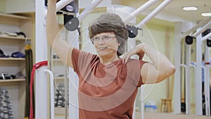 Elderly woman stretching out, doing physiotherapy exercises in fitness room. Healthy gymnastics. Active seniors.