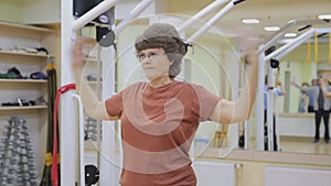 Elderly woman stretching out, doing physiotherapy exercises in fitness room. Healthy gymnastics. Active seniors.