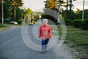 An elderly woman strolls through the village. Nature.