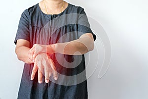 Elderly woman suffering with parkinson disease symptoms on hand while standing on white background