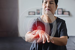 Elderly woman suffering with parkinson disease symptoms on hand while standing on white background