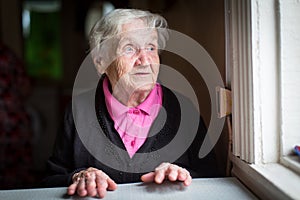 Elderly woman surprised stares out of the window. Happy.