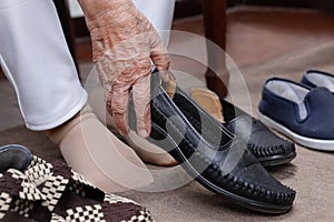 Elderly woman swollen feet putting on shoes photo