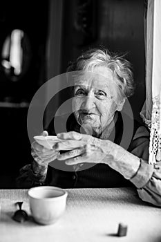 An elderly woman at the table drinking tea from the saucer.