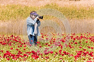 Elderly woman taking pictures of field with flowers