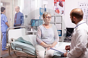 Elderly woman talking with doctor in hospital cabinet
