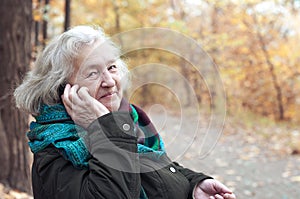 Elderly woman talking on the phone in an autumn park