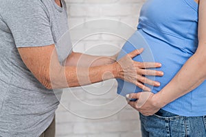 An elderly woman touches the belly of her pregnant daughter. Close-up.