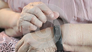 Elderly woman touches wristband of pulse monitor