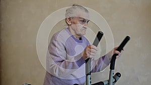 Elderly woman is training at home on the training apparatus