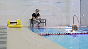 Elderly woman trains in swimming pool with trainer