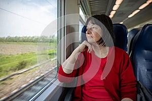 Elderly woman travelling solo by train, looking through out the window