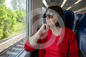 Elderly woman travelling solo by train, looking through out the window