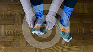 Elderly woman tries on leg sock from wool yarn