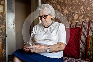 Elderly woman using mobile phone at home