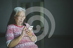 Elderly woman using a phone in a wheelchair