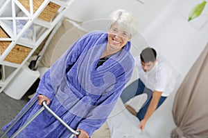 Elderly woman using zimmer frame in home