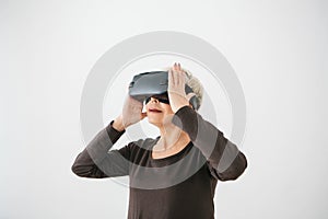 An elderly woman in virtual reality glasses. An elderly person using modern technology.