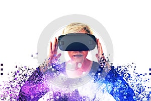 An elderly woman in virtual reality glasses is scattered by pixels. Conceptual photography with visual effects with an