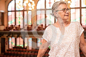 Elderly woman visiting the house of music in Barcelona. in the background the seats and the artistic stained glass windows