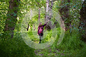 Elderly woman walking in green forest. Spring time.