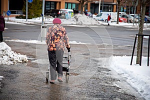 Elderly woman walking with the help of a walker in a snowy winter