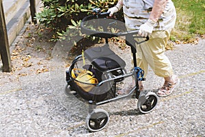 Elderly woman walking outside with rollator or wheeled walker