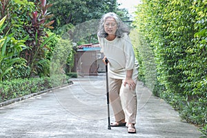 Elderly woman walking on the road She has knee pain due to osteoporosis.