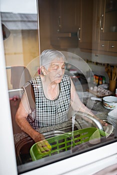 Elderly woman washing dishes