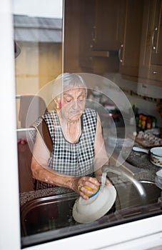 Elderly woman washing dishes