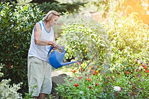 Elderly woman watering plants in her garden