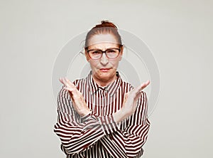 elderly woman wearing casual style rejection expression crossing arms doing negative sign over grey background