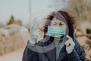 Elderly woman wearing facial mask and gloves to prevention of infection