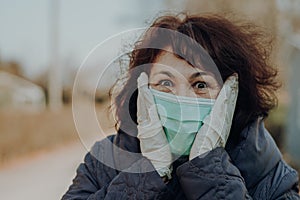 Elderly woman wearing facial mask and gloves to prevention of infection