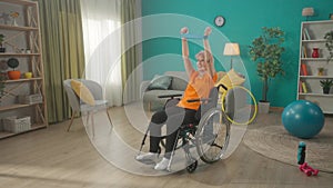 An elderly woman in a wheelchair is exercising with a sports elastic band in the living room. An elderly grayhaired