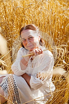 Elderly woman in white walking through wheat field